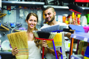 Young happy russian housewife chooses broom for cleaning